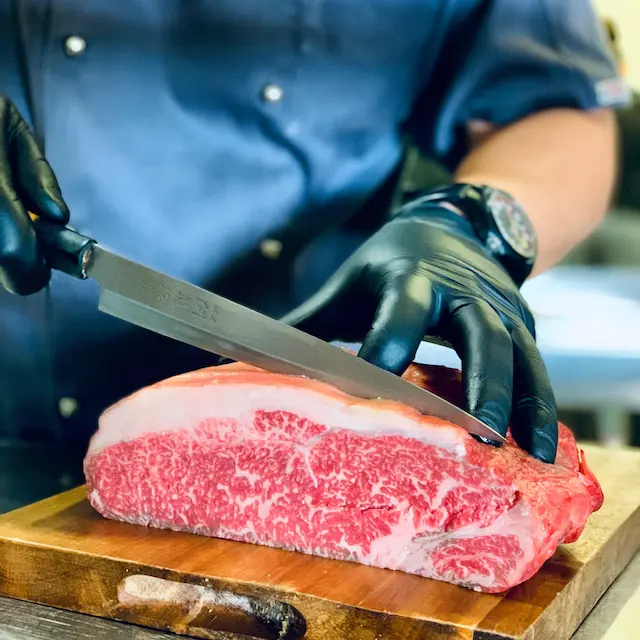 Closeup of a chef cutting meat with a knife